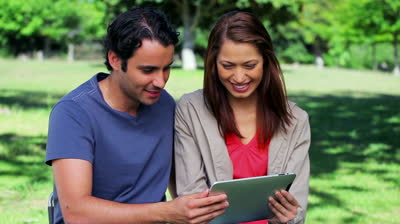 Couple using tablet computer in the park.